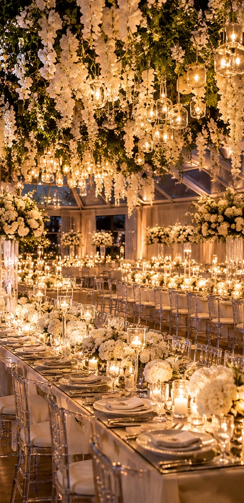 Candlelit wedding reception with hanging white wisteria and long tables of white florals